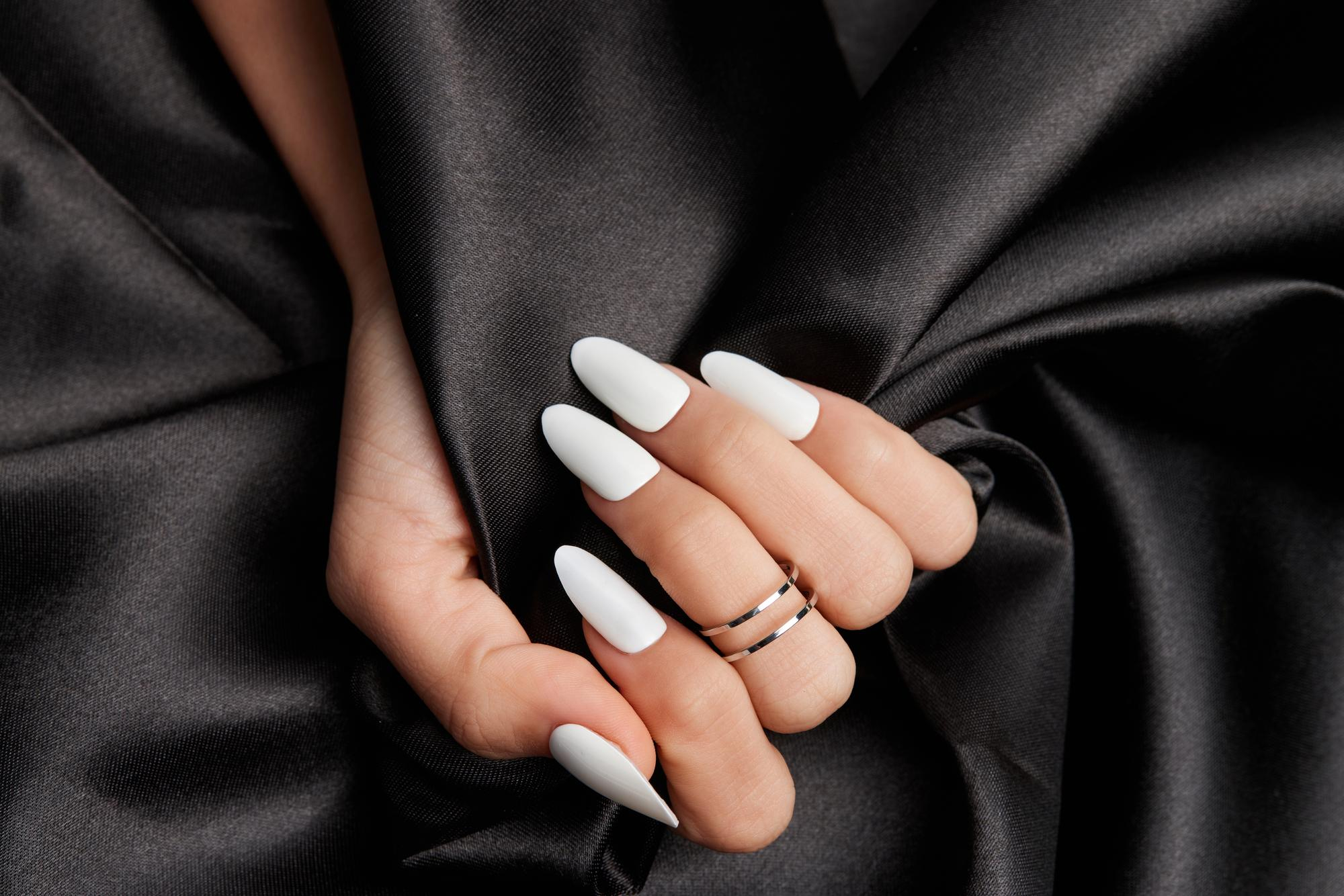 female-hand-with-long-white-nails-holding-black-satin-fabric